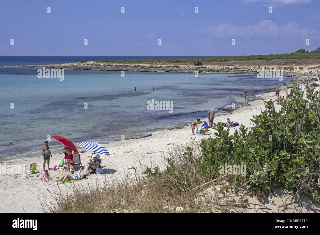 I turisti italiani nuotano e prendono il sole sulla spiaggia di sabbia in estate lungo il Mar Ionio nella provincia di Lecce, nella regione Puglia nel sud Italia Foto Stock