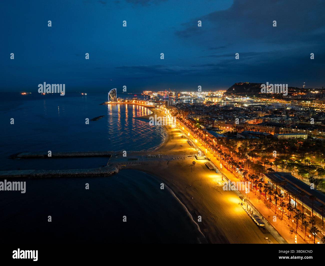 Vista aerea al crepuscolo delle spiagge illuminate di Barcellona e dei riflessi della città Foto Stock