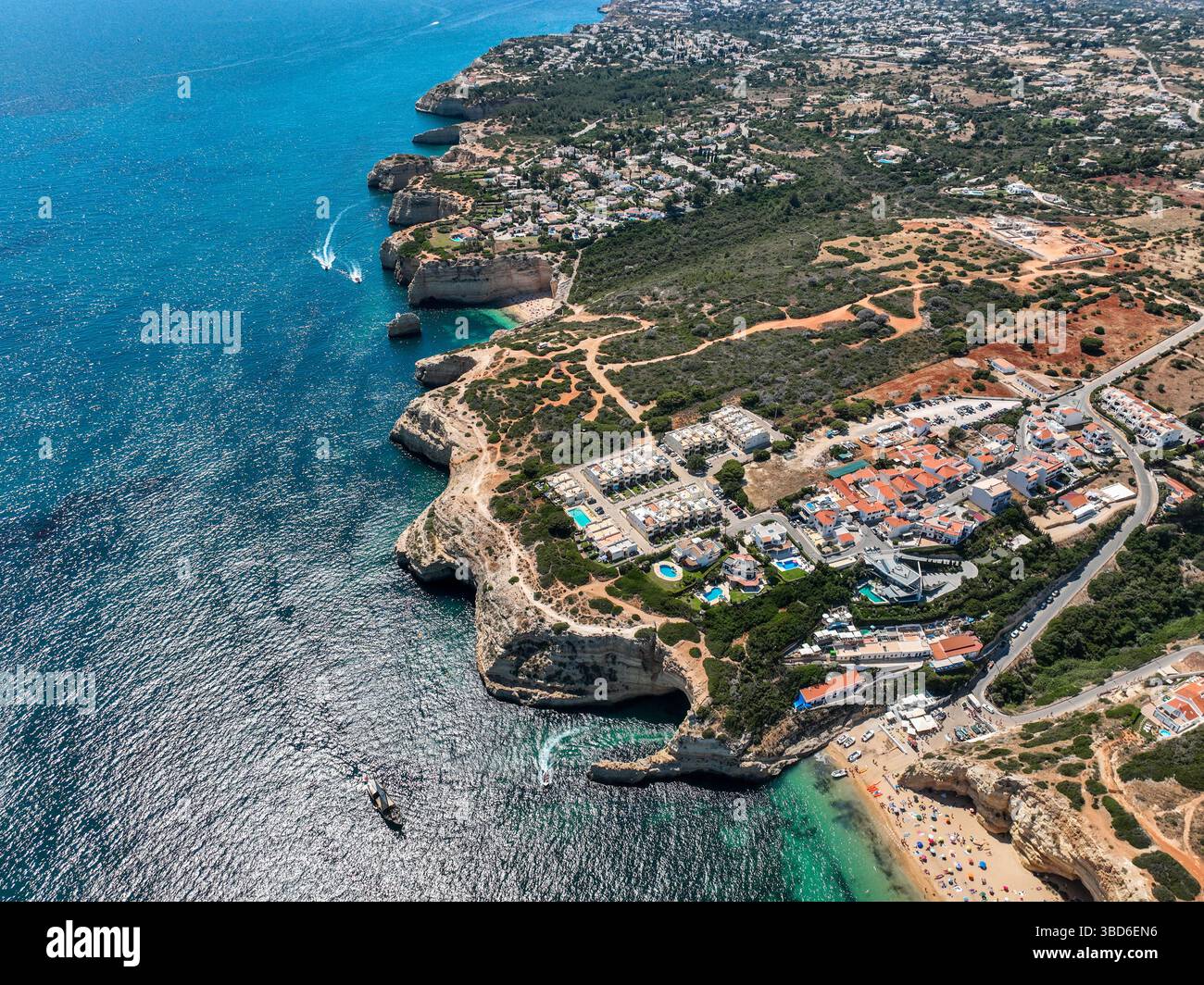 Aspre scogliere dell'Algarve con area boschiva e acque turchesi dall'alto Foto Stock