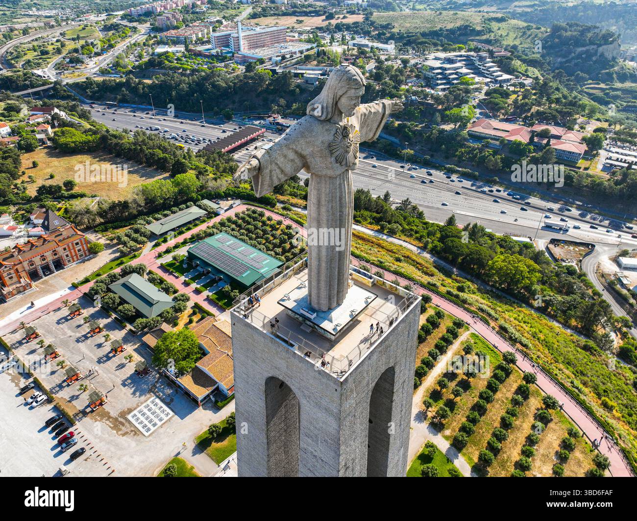 Almada, Portogallo - 14 maggio 2024: Veduta aerea dell'imponente monumento al Cristo Re circondato da vegetazione e strade Foto Stock