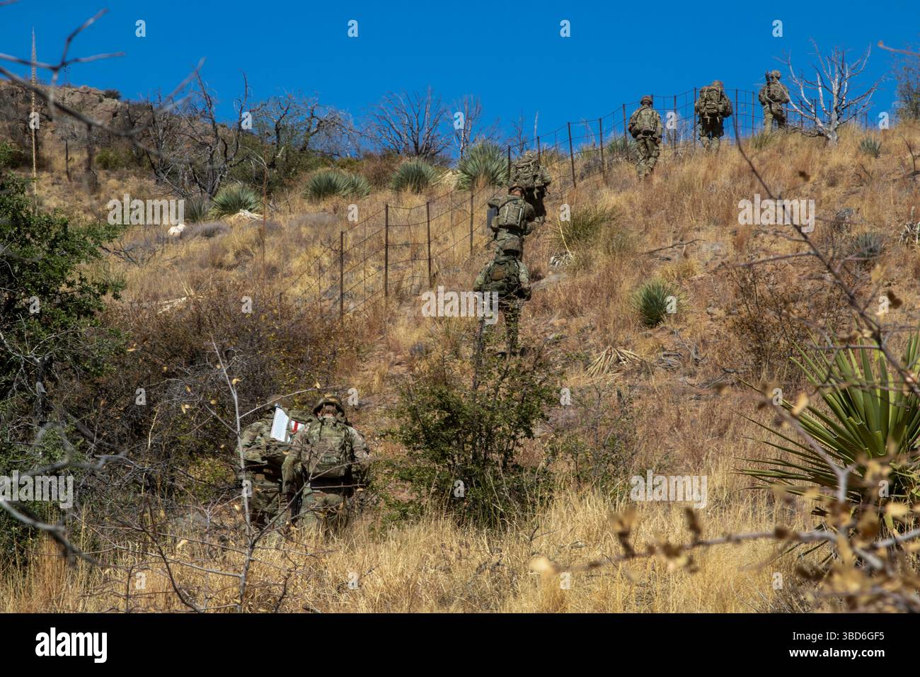 Soldati statunitensi, assegnati alla 76th Engineer Company, 41st Engineer Battalion, sotto Joint Task Force–Southern Border, attraversano terreni ripidi trasportando equipaggiamenti durante una missione di messa in deposito di segni della New Mexico National Defense area (NMNDA) vicino ad Antelope Wells, New Mexico, 20 maggio 2025. Sotto la direzione del Northern Command degli Stati Uniti, la Joint Task Force–Southern Border allinea gli sforzi per sigillare il confine meridionale e respingere le attività illegali ed è responsabile di operazioni su larga scala, agili e di tutti i domini, che consentiranno operazioni DoD più efficaci ed efficienti. (Foto U.S. Army di SPC. Anjelica ASE Foto Stock