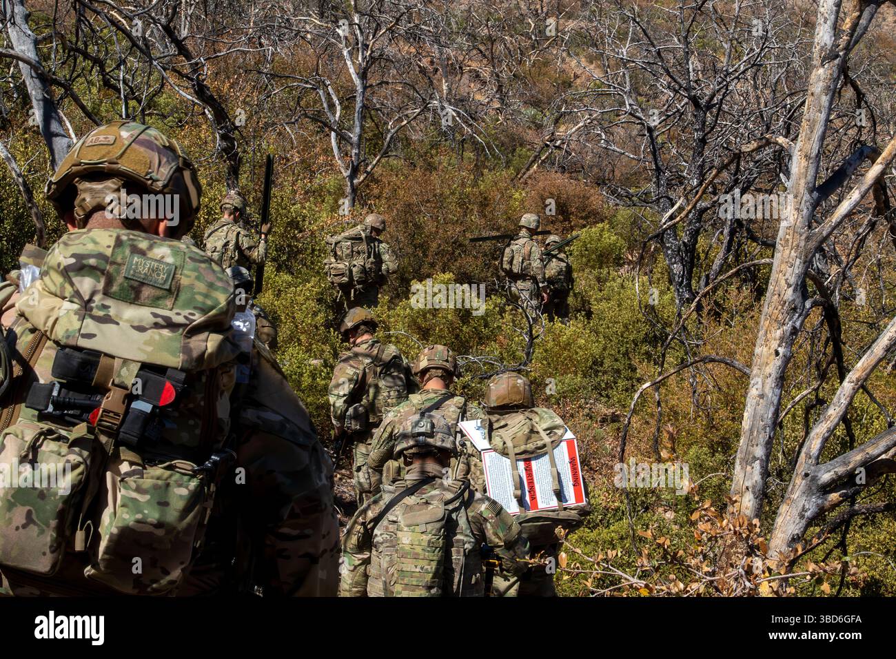 I soldati statunitensi, assegnati alla 76th Engineer Company, 41st Engineer Battalion, con Joint Task Force–Southern Border, si muovono attraverso la fitta vegetazione durante il trasporto di materiali durante una missione di deposito di segni della New Mexico National Defense area (NMNDA) vicino ad Antelope Wells, New Mexico, 20 maggio 2025. Sotto la direzione del Northern Command degli Stati Uniti, la Joint Task Force–Southern Border allinea gli sforzi per sigillare il confine meridionale e respingere le attività illegali ed è responsabile di operazioni su larga scala, agili e di tutti i domini, che consentiranno operazioni DoD più efficaci ed efficienti. (Foto U.S. Army di S Foto Stock