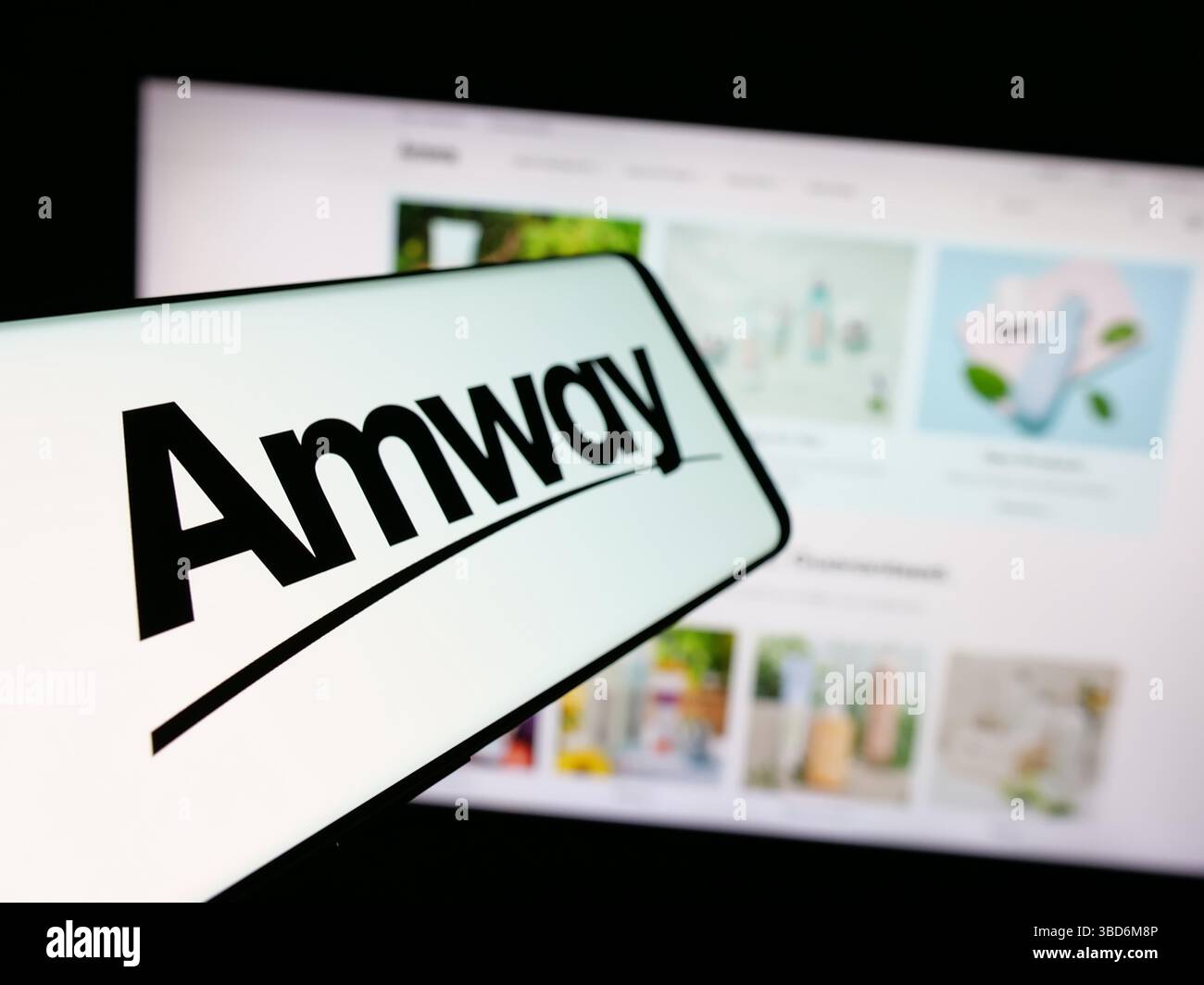 In questa immagine, uno smartphone con il logo della società di marketing multilivello statunitense Amway Corp. È visibile sullo schermo davanti al sito Web. Foto Stock
