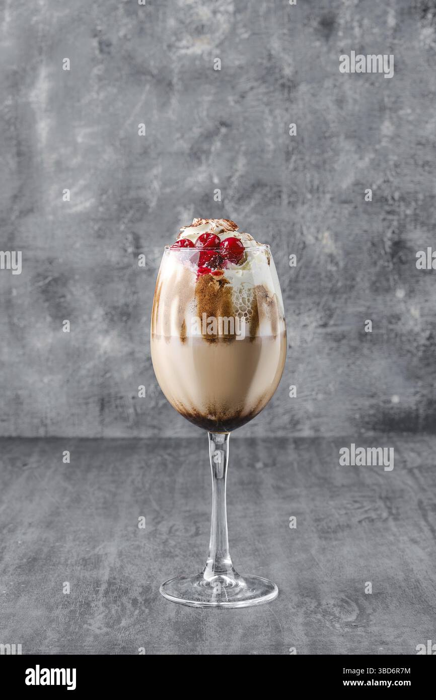 Bicchiere di caffè freddo con panna montata e ciliegia su sfondo grigio scuro Foto Stock