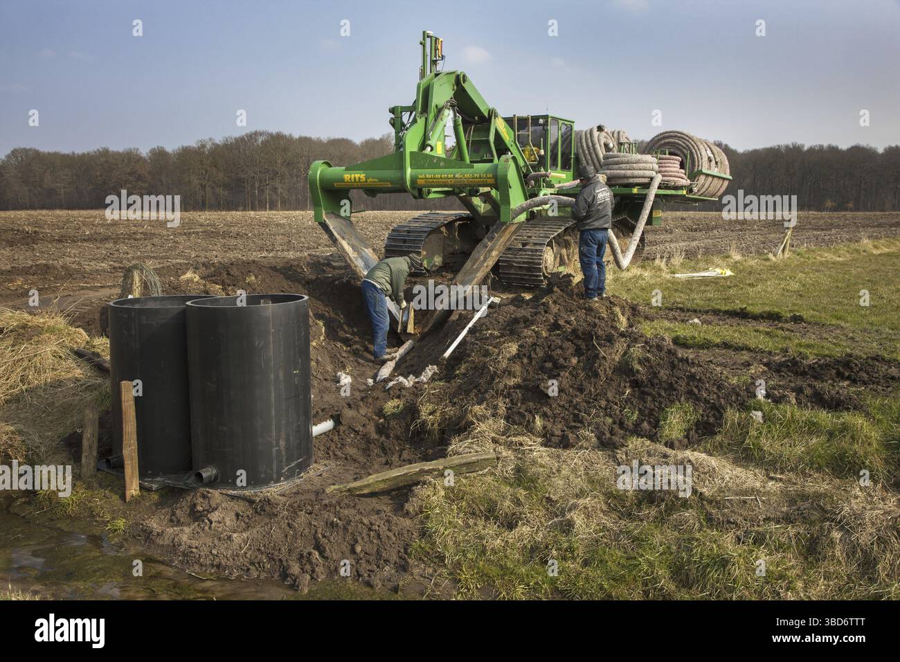 Appaltatori che lavorano con scavatrincee di drenaggio e aratro piastrellato su terreni agricoli Foto Stock