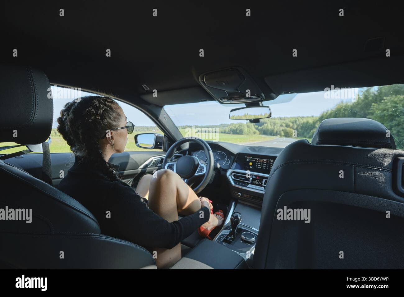 Bella donna seduta dietro il volante in un'auto potente Foto Stock