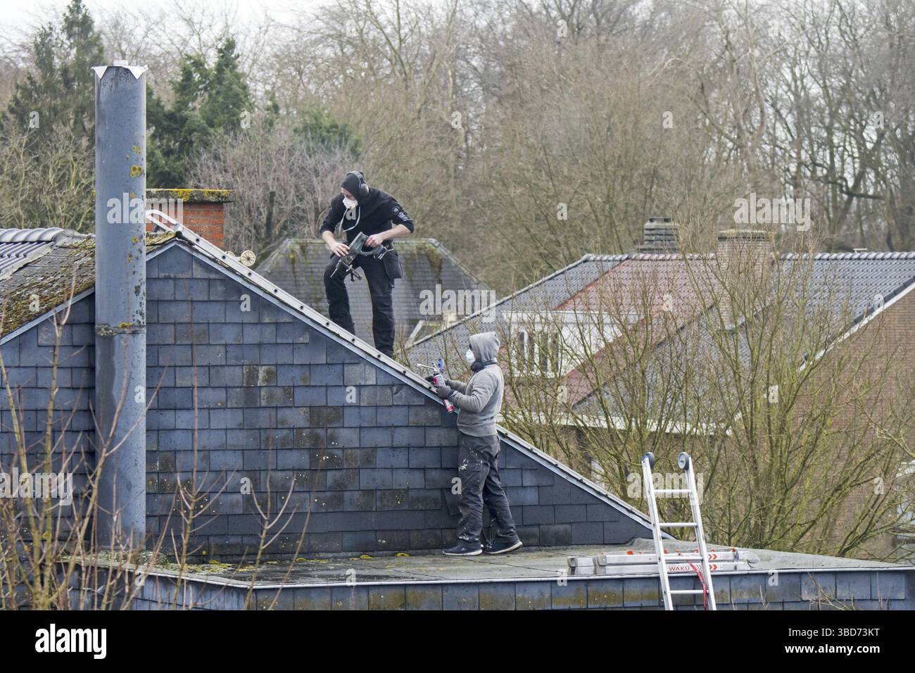 Tetti, appaltatori di tetti che lavorano sul tetto per lavori di riparazione in un giorno di tempesta dopo il passaggio delle tempeste Eunice e Franklin nel febbraio 2022 Foto Stock