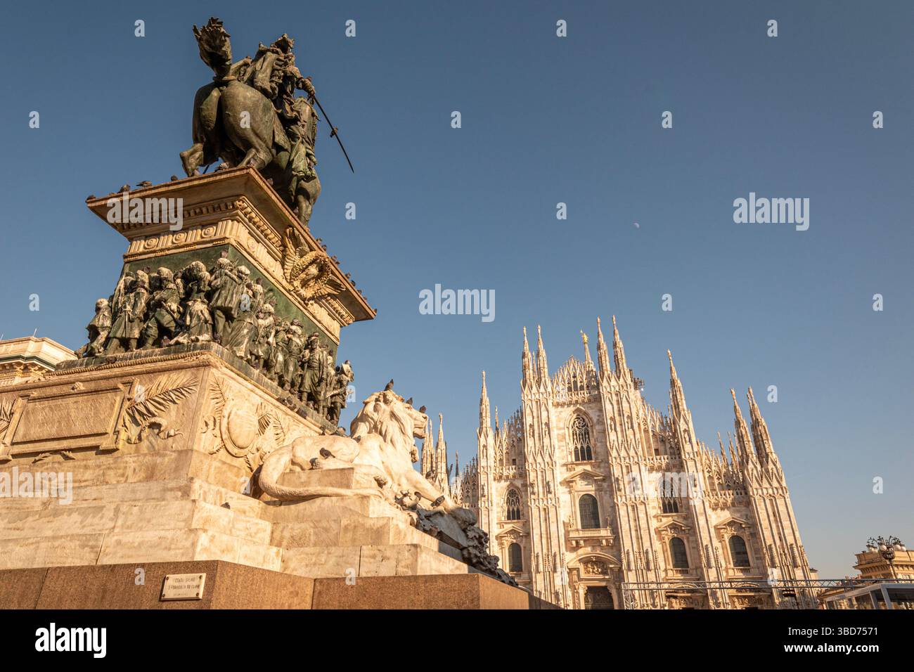 Vista serale del Duomo di Milano illuminato nel cuore della città, con persone che camminano su Piazza del Duomo. La scena si riflette Foto Stock