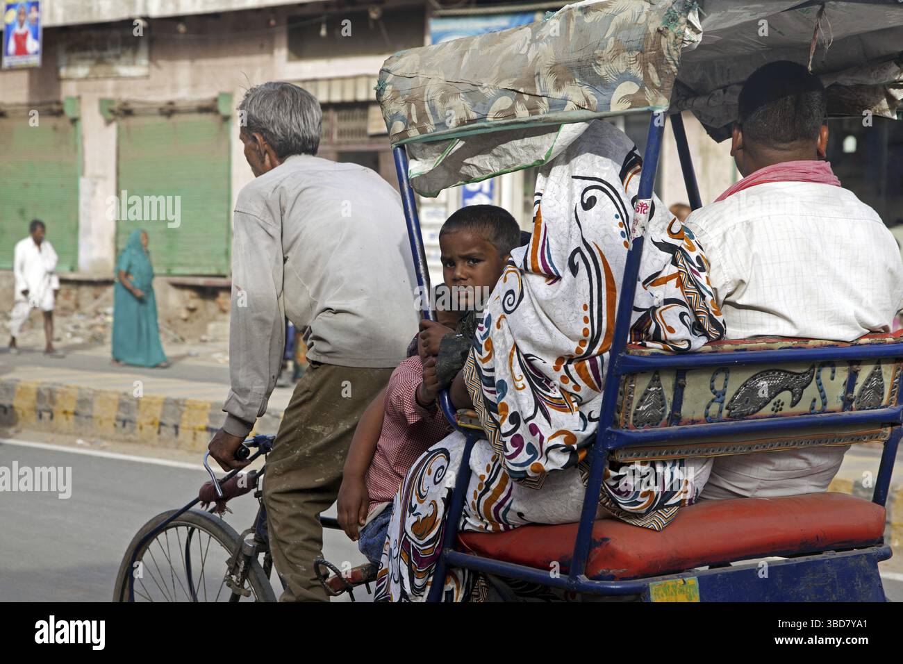 Pedala in risciò con un vecchio autista che trasporta la famiglia come trasporto urbano a Mathura, India Foto Stock
