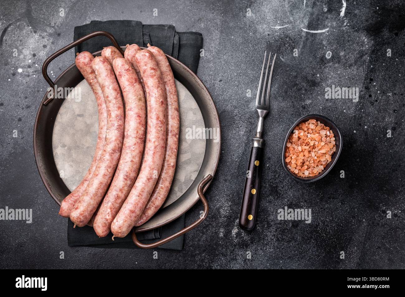 Primo piano di salsicce crude crude con la sua consistenza succosa, ideale per piatti saporiti e creatività culinaria. sfondo nero. vista dall'alto. Foto Stock