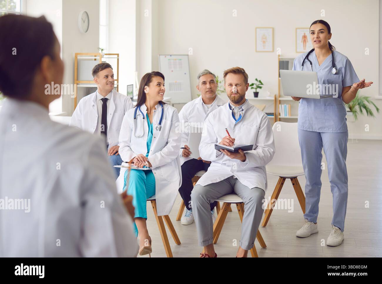 Team medico diversificato di giovani infermieri, medici discutere piano medico alla riunione tenendo portatile Foto Stock