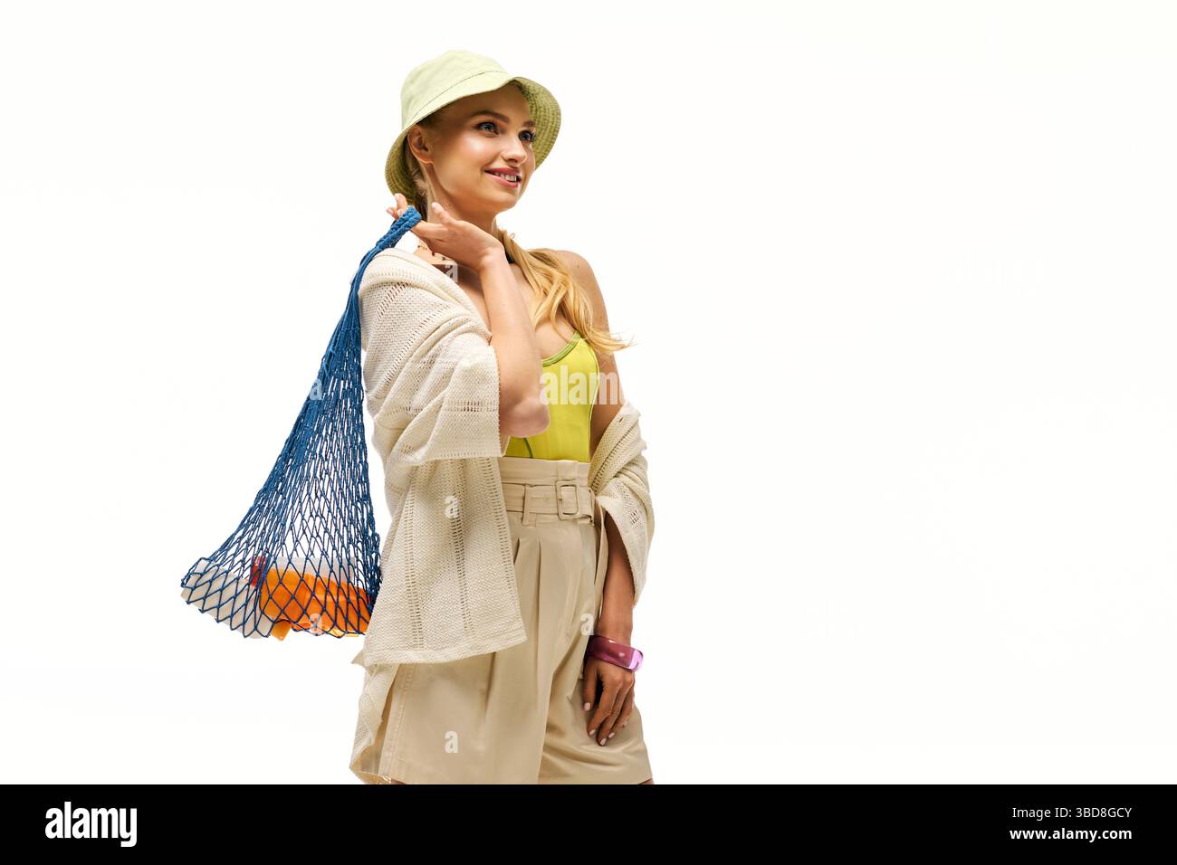 La bella giovane donna sorride mentre porta con sé una borsa tote colorata in una giornata di sole all'aperto. Foto Stock