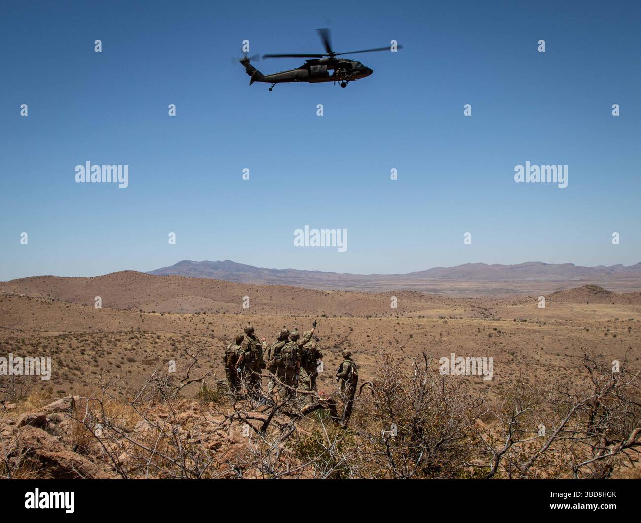 I soldati statunitensi con la 76th Engineer Company, assegnati alla Joint Task Force-Southern Border, salutano un elicottero UH-60 Black Hawk dell'esercito statunitense assegnato alla 1st Combat Aviation Brigade, 1st Infantry Division, durante una missione aerea per consegnare i segnali della New Mexico National Defense area (NMNDA) vicino ad Antelope Wells, New Mexico, 20 maggio 2025. I materiali sono stati forniti dalla consegna aerea a causa del terreno austero che limitava le manovre a terra. Sotto la direzione del Northern Command degli Stati Uniti, la Joint Task Force–Southern Border allinea gli sforzi per sigillare il confine meridionale e respingere le attività illegali ed è responsabile della completa scal Foto Stock