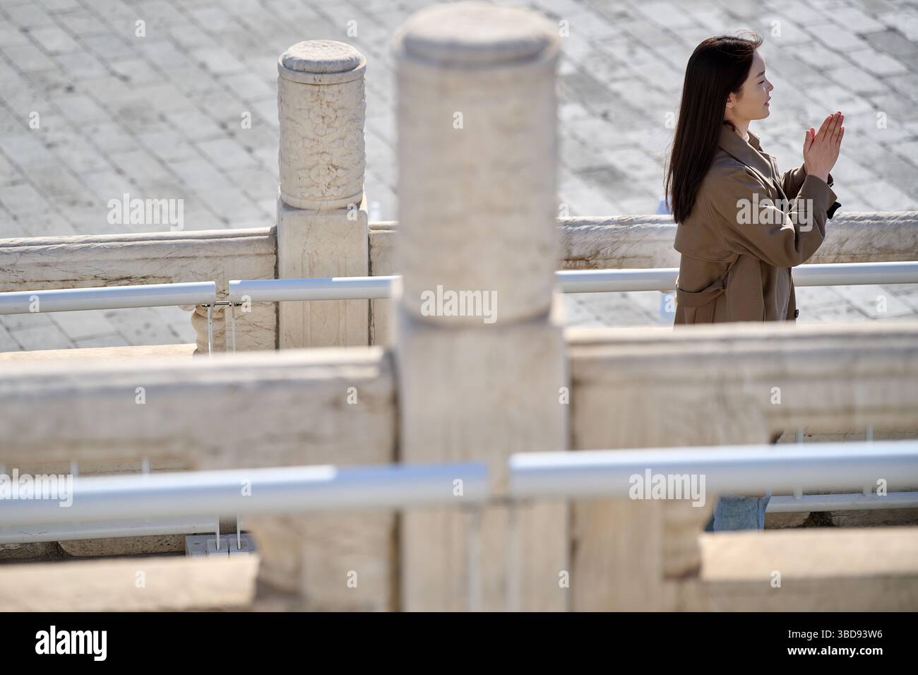 Mani agganciate nella preghiera silenziosa accanto all'antica ringhiera di pietra alla luce del mattino Foto Stock