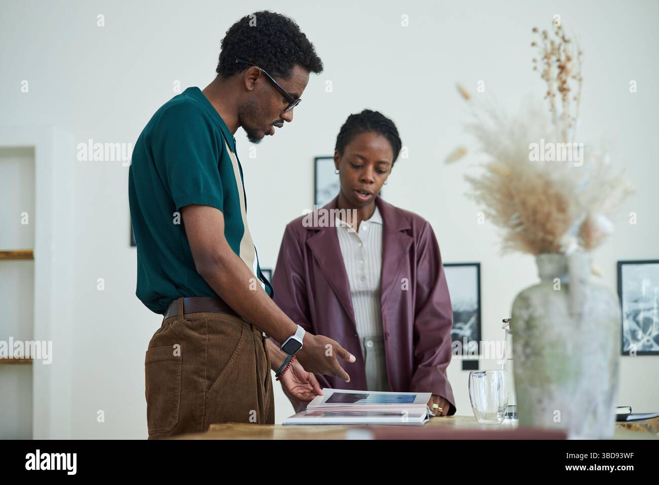 Coppia afroamericana che recensisce album con foto e ne discute nello spazio di gallerie d'arte moderne Foto Stock