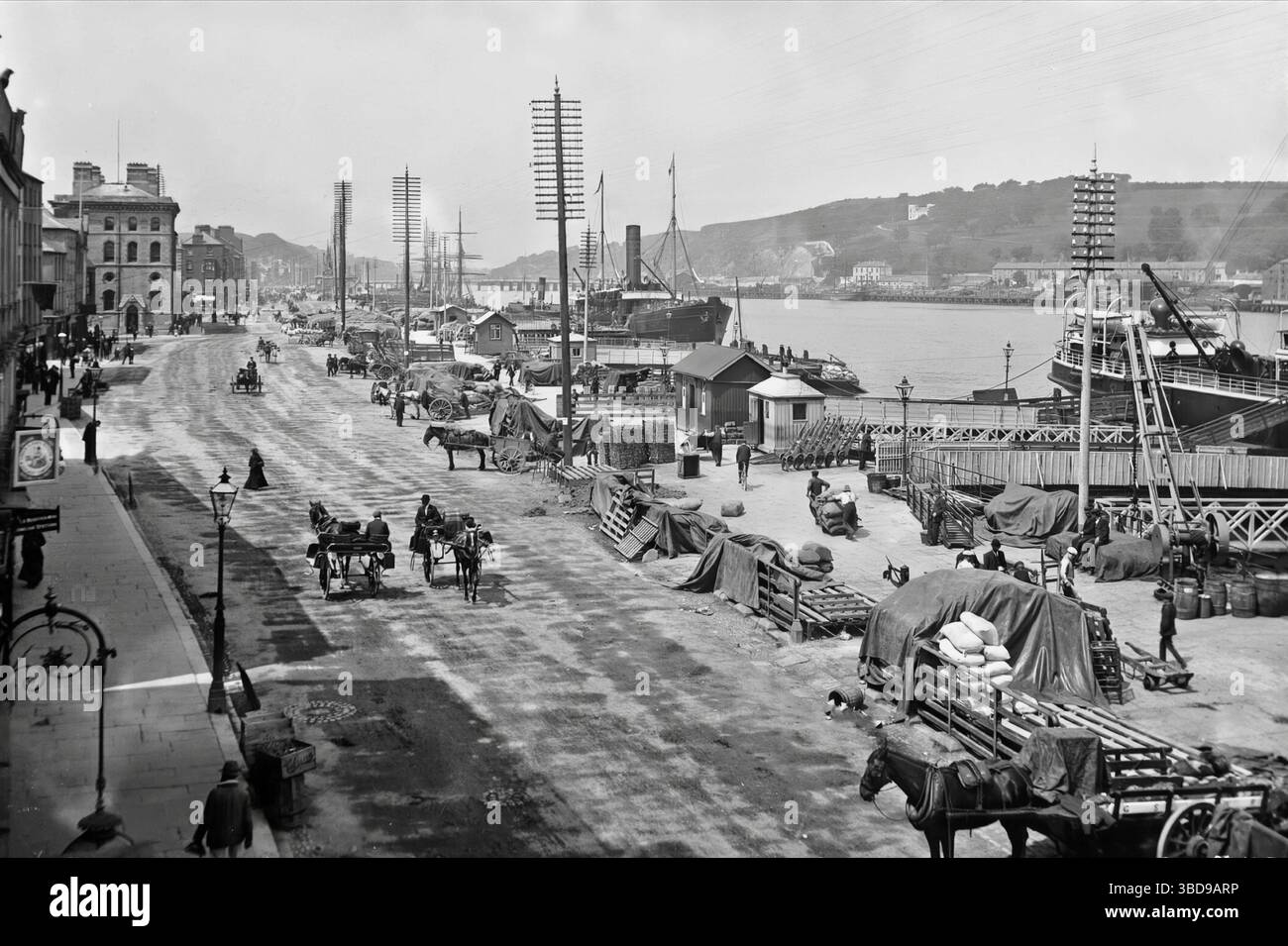 Una fotografia dei primi anni del XX secolo dei (South) Quays che costeggiano il fiume Suir mentre scorre attraverso Waterford City, in Irlanda. Nei primi anni '1700, il consiglio comunale abbatté le mura che si affacciano sul fiume e usa i resti per rendere le banchine più ampie e più adatte al commercio. I mercanti si trasferirono rapidamente e Waterford divenne un importante porto irlandese e un importante creatore di posti di lavoro in città. Le merci sono state scaricate, caricate e trasportate a mano lungo le banchine. Foto Stock