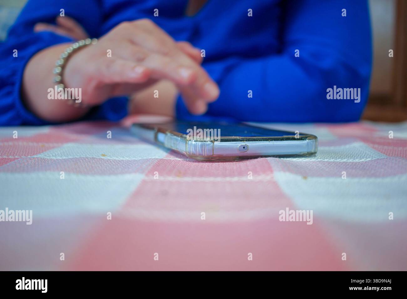 una donna sta controllando il suo cellulare su un tavolo Foto Stock