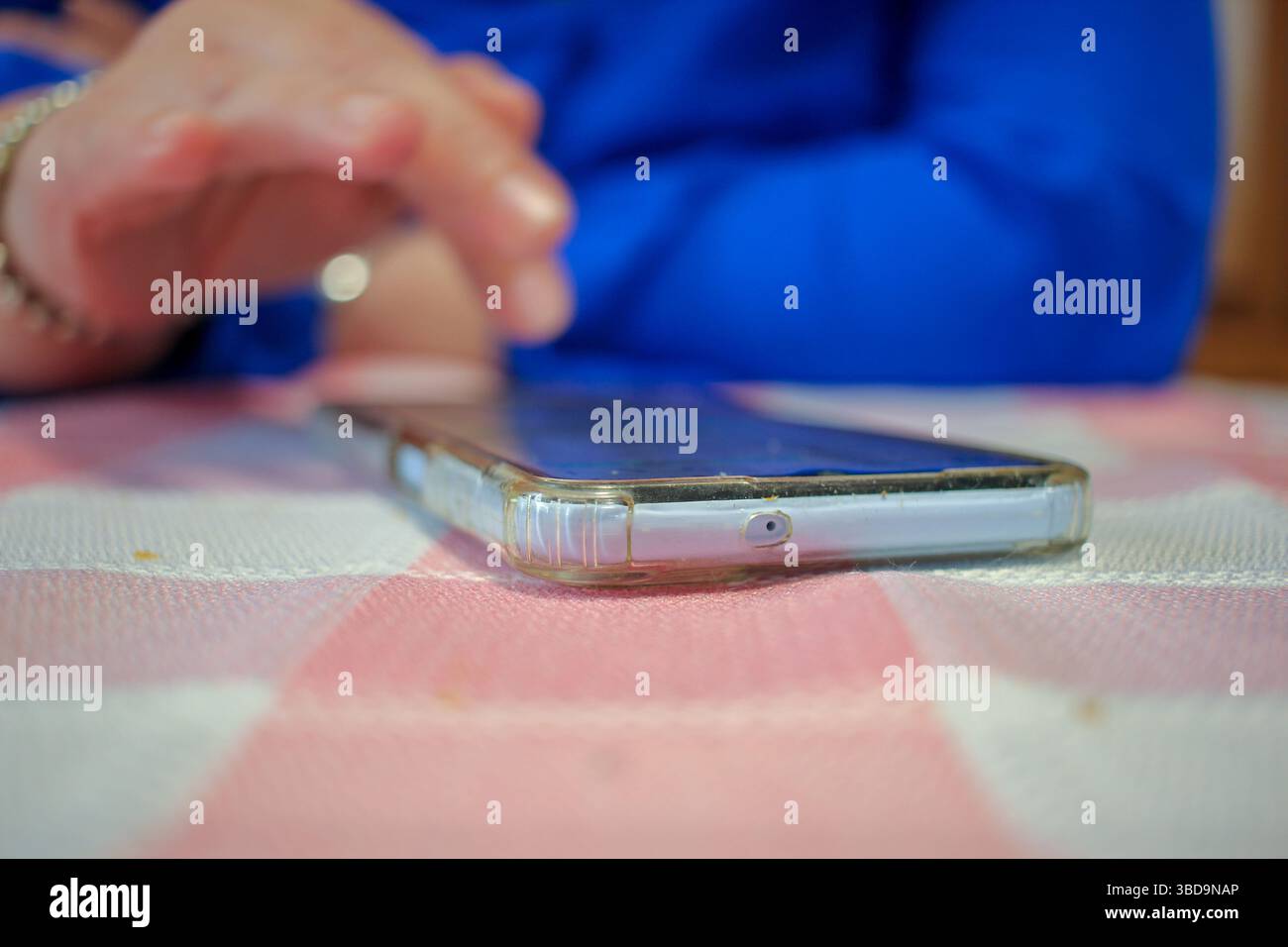una donna sta controllando le notizie su un cellulare su un tavolo Foto Stock