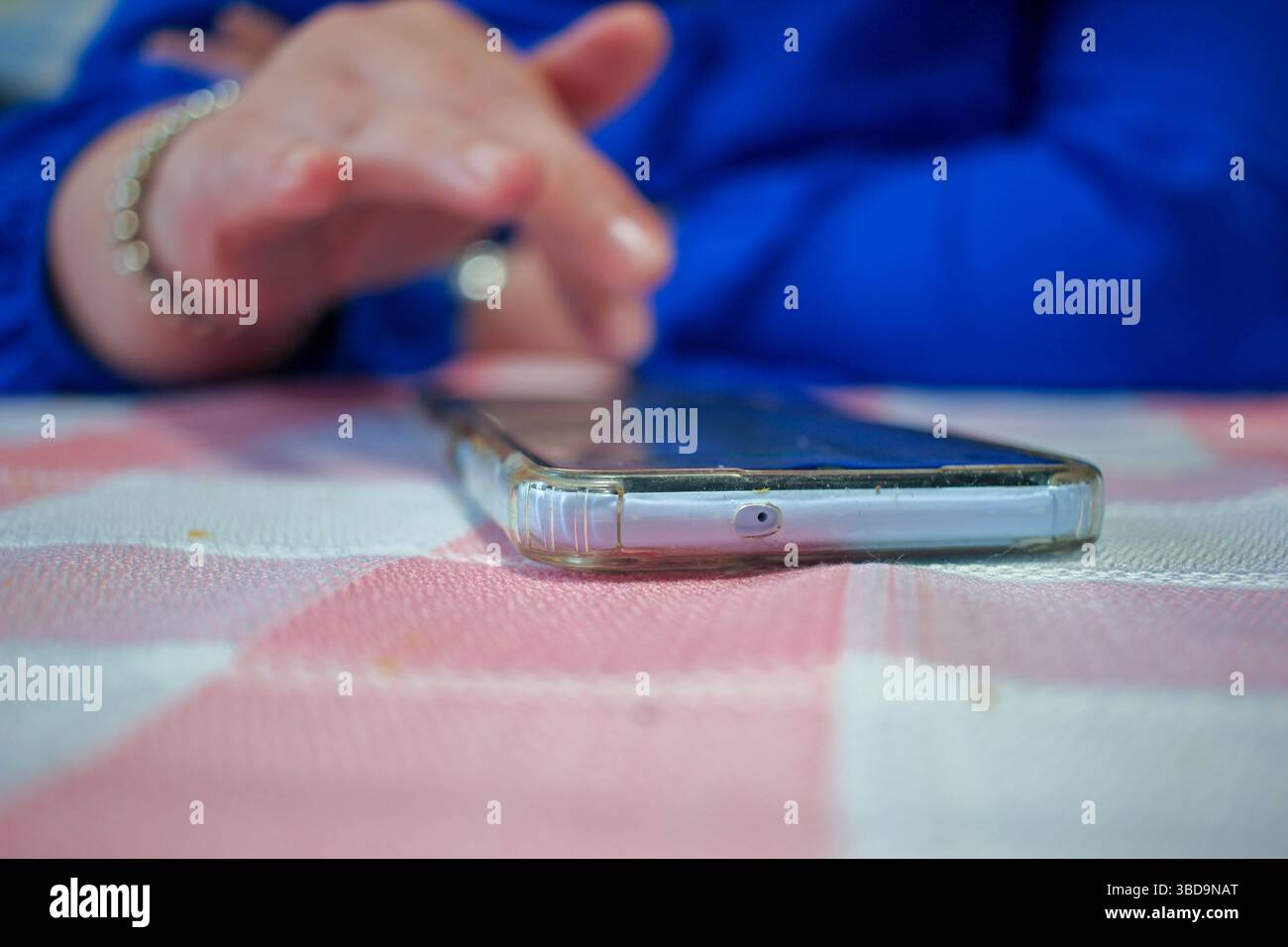 donna che tocca uno schermo mobile su un tavolo Foto Stock