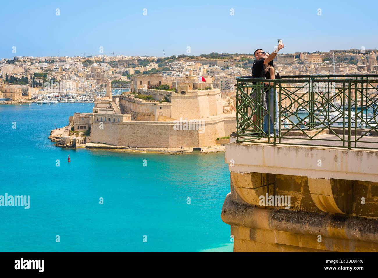 La Valletta Malta estate, vista di una giovane coppia che posa nei giardini di Upper Barrakka mentre si fotografa contro il Grand Harbour, la Valletta, Malta Foto Stock