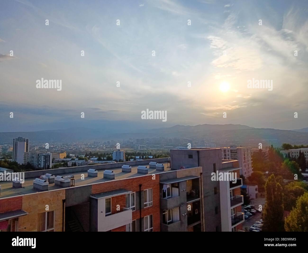 Tramonto panoramico su Tbilisi, Georgia, con una luce dorata soffusa che illumina lo skyline della città e le sagome delle montagne. Una fine pacifica e calda del Foto Stock