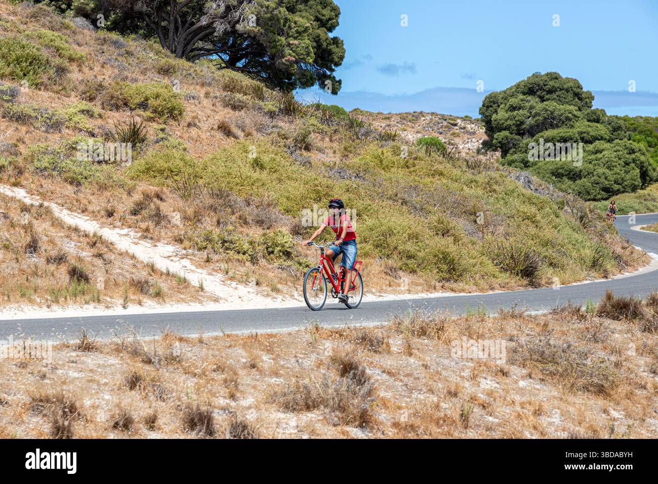 Un ciclista su Parker Point Road visto dalla Oliver Hill Railway, Rottnest Island, (Wadjemup) Western Australia, WA, Australia. Foto Stock