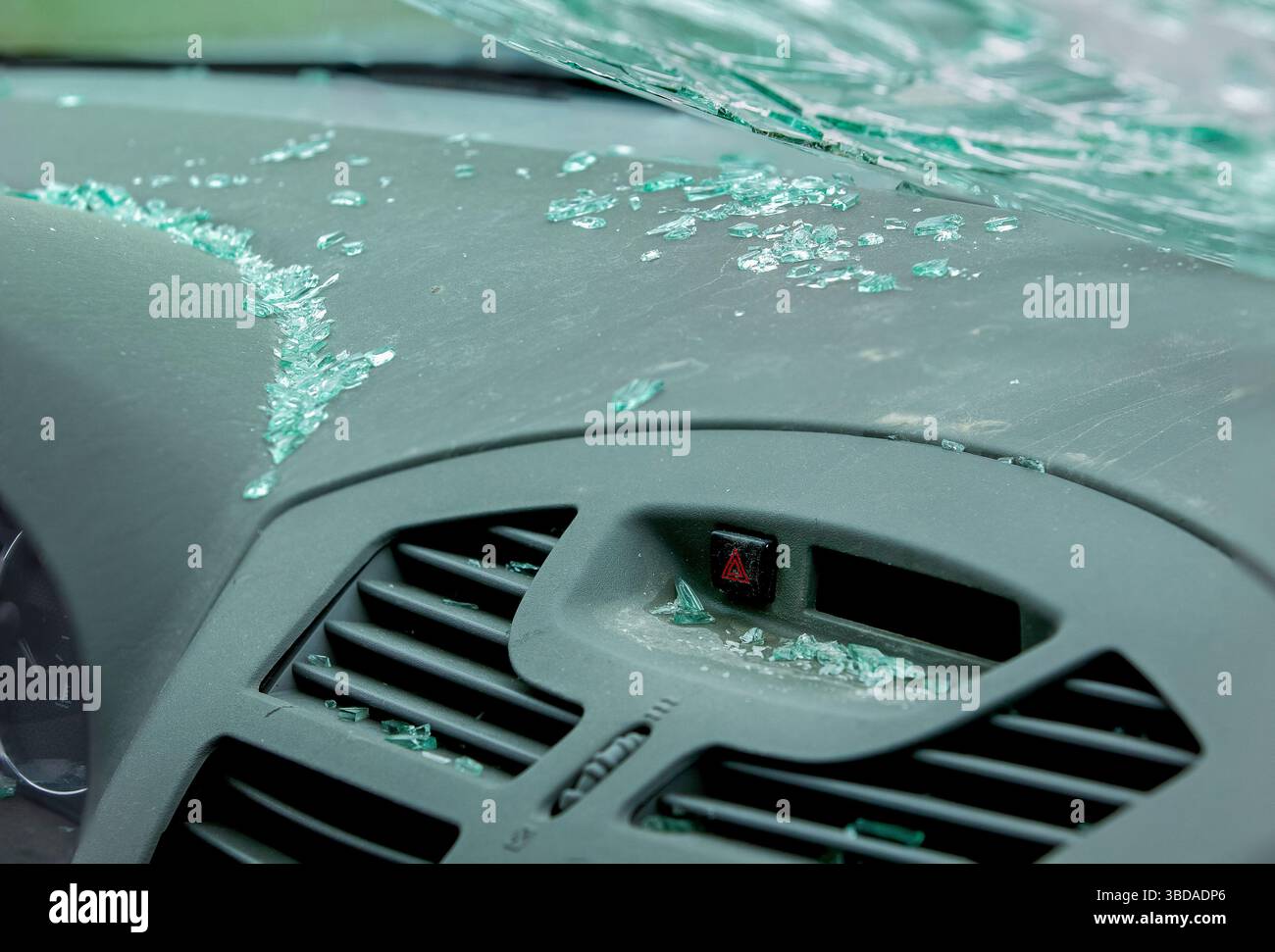 Vetri rotti sparsi sul cruscotto dell'auto polveroso sotto il parabrezza incrinato. Abitacolo del veicolo dopo una collisione frontale. Foto Stock