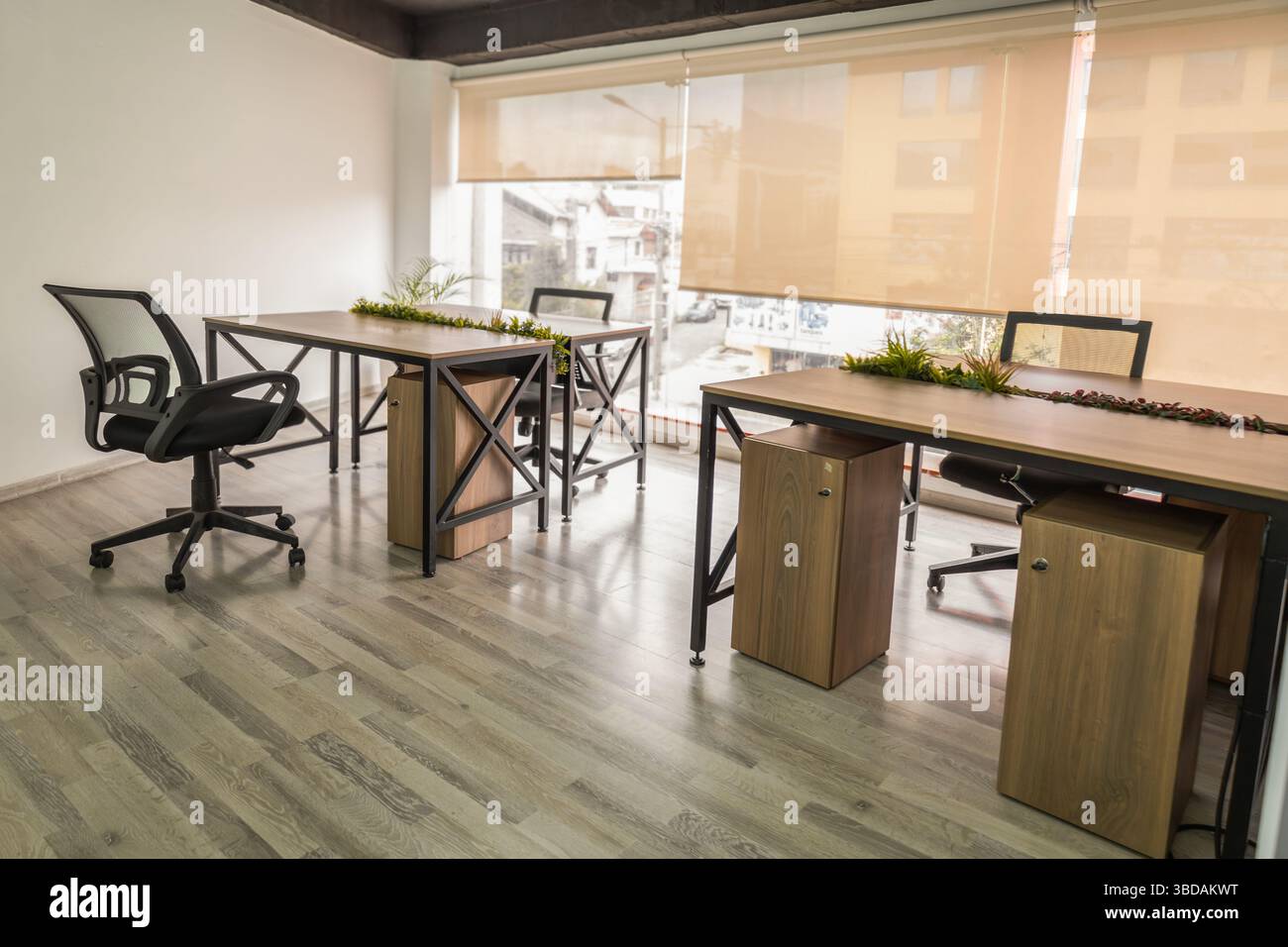 Una spaziosa sala riunioni con tavoli, sedie e una grande finestra che riempie lo spazio di luce naturale, creando un atmos luminoso e professionale Foto Stock