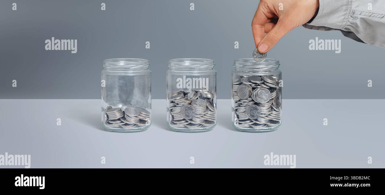 Tre vasetti di vetro con monete come diagramma. Mano femminile che mette la moneta. Isolato su grigio. Risparmio, finanza, prestiti, concetto di pensione Foto Stock