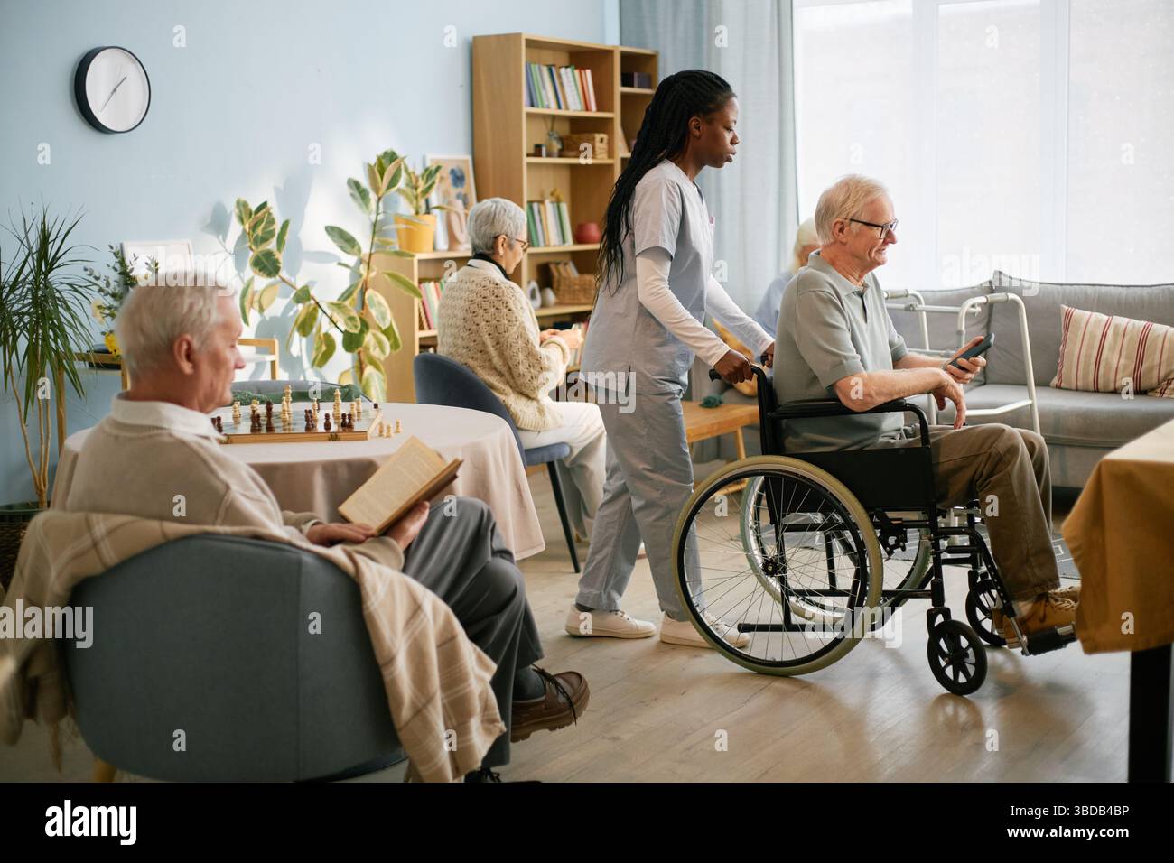 Infermiere che assiste gli anziani su sedia a rotelle Foto Stock