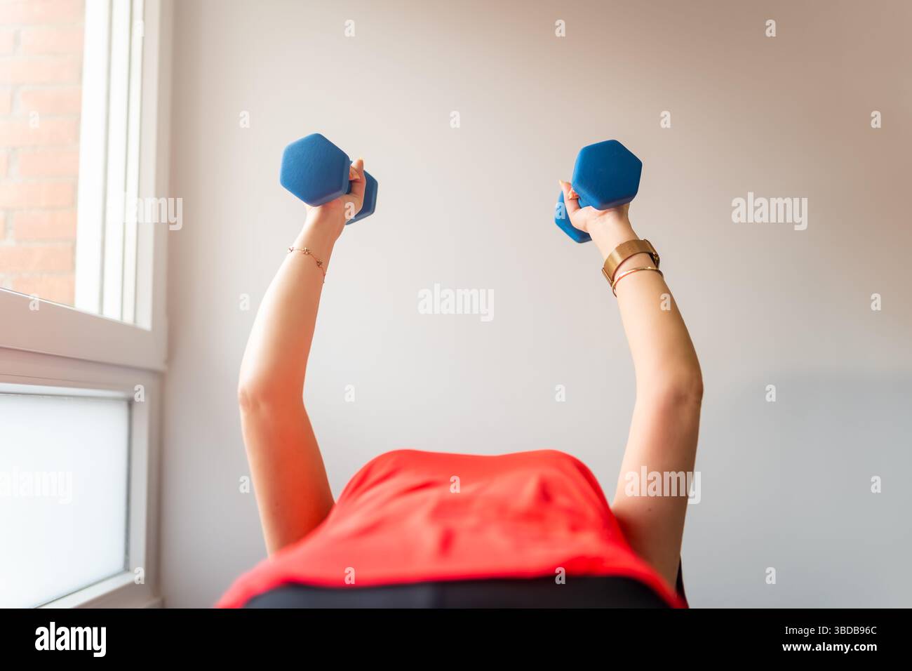 Donna che fa esercizi di forza con piccoli manubri per rafforzare le braccia Foto Stock