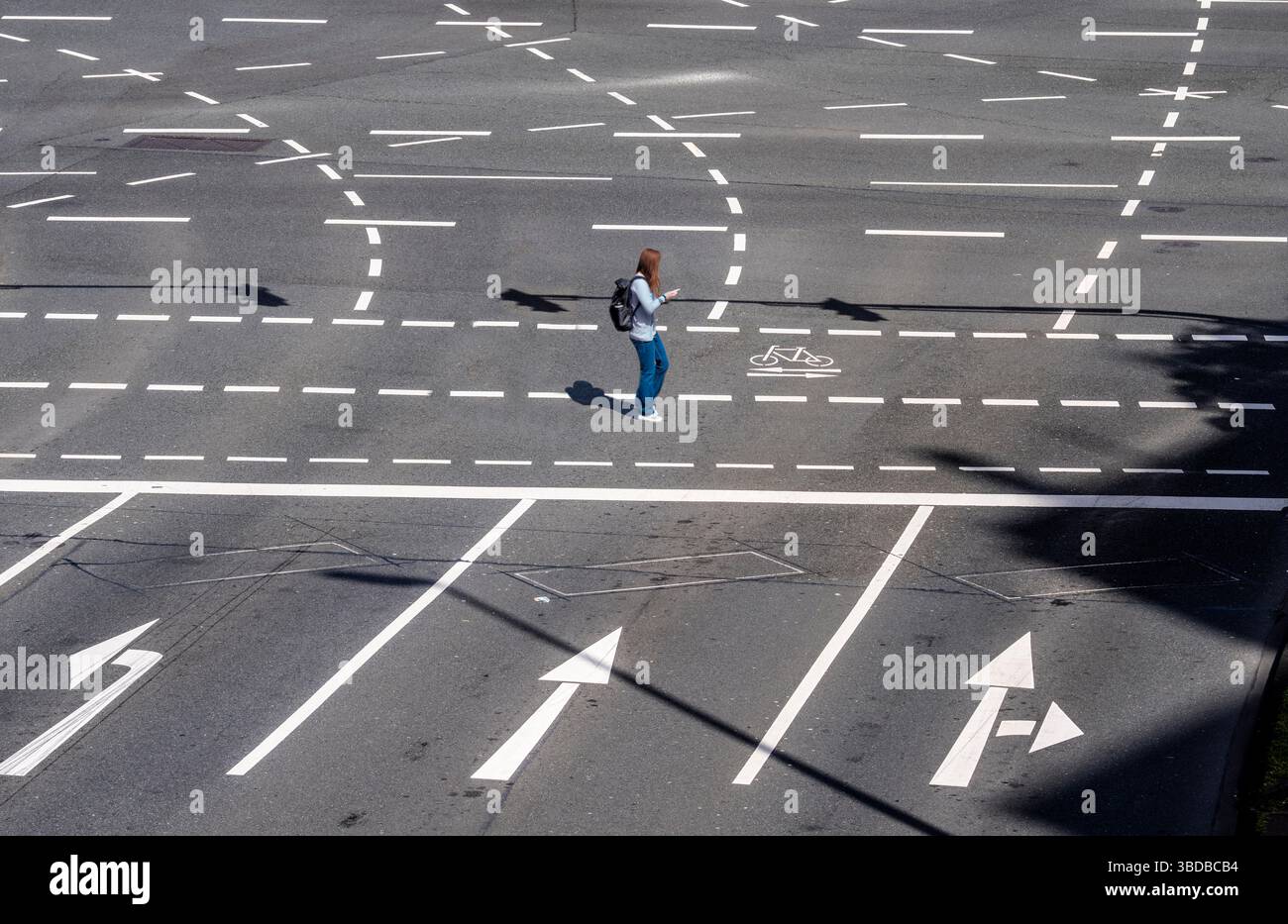Segnaletica di un incrocio stradale a più corsie, corsie per i veicoli in curva, pedoni, ciclisti, automobilisti, frecce di direzione, ombre del semaforo p Foto Stock