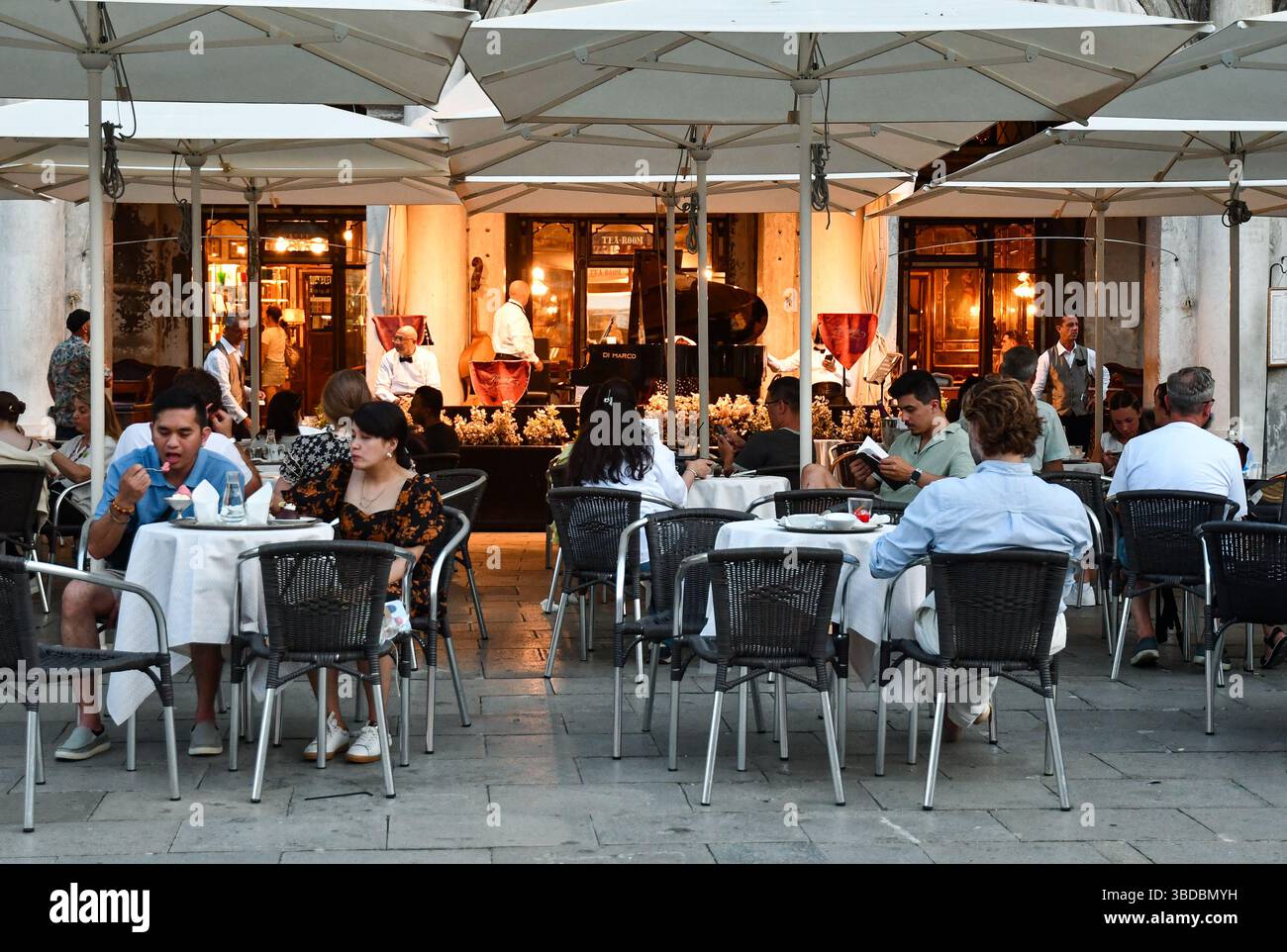 I turisti possono gustare gelati e bevande al caffè Florian, una storica caffetteria aperta nel 1720 in Piazza San Marco, Venezia, Veneto, Italia Foto Stock