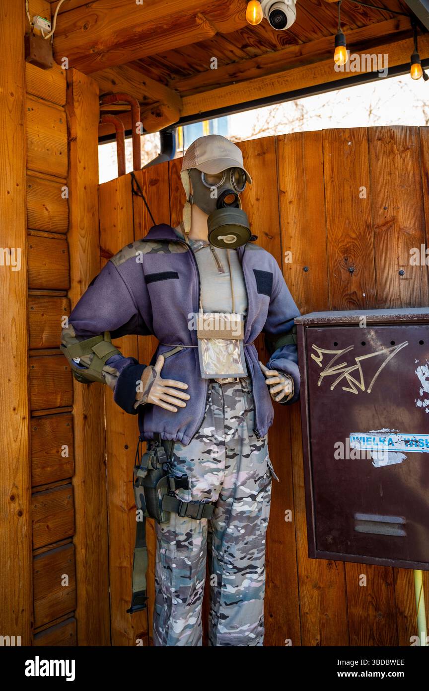 Manichino vestito con pantaloni mimetici militari, giubbotto tattico e maschera antigas, esposto all'esterno di un edificio in legno a Zakopane, Polonia Foto Stock