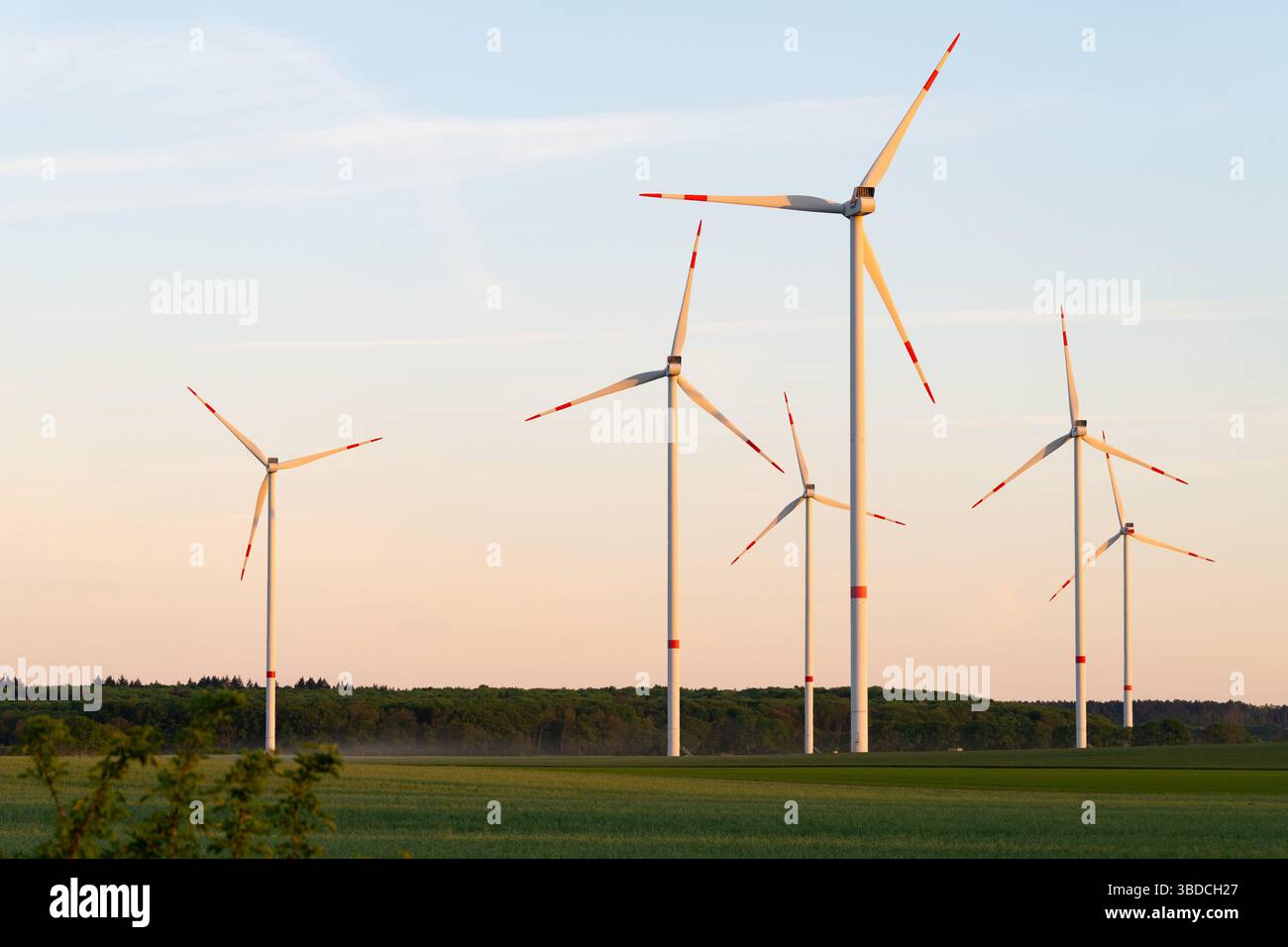 Turbine eoliche al tramonto. Splendido paesaggio con una centrale eolica in Germania. Generazione di energia verde e futuristica. Foto Stock
