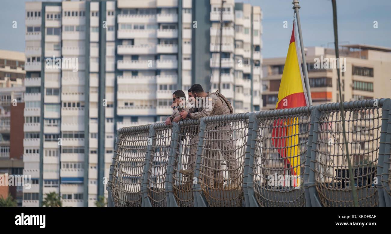 Spagna Malaga 1 28 2024 due militari in mimetizzazione in un ambiente urbano con bandiera spagnola su una recinzione. Foto Stock