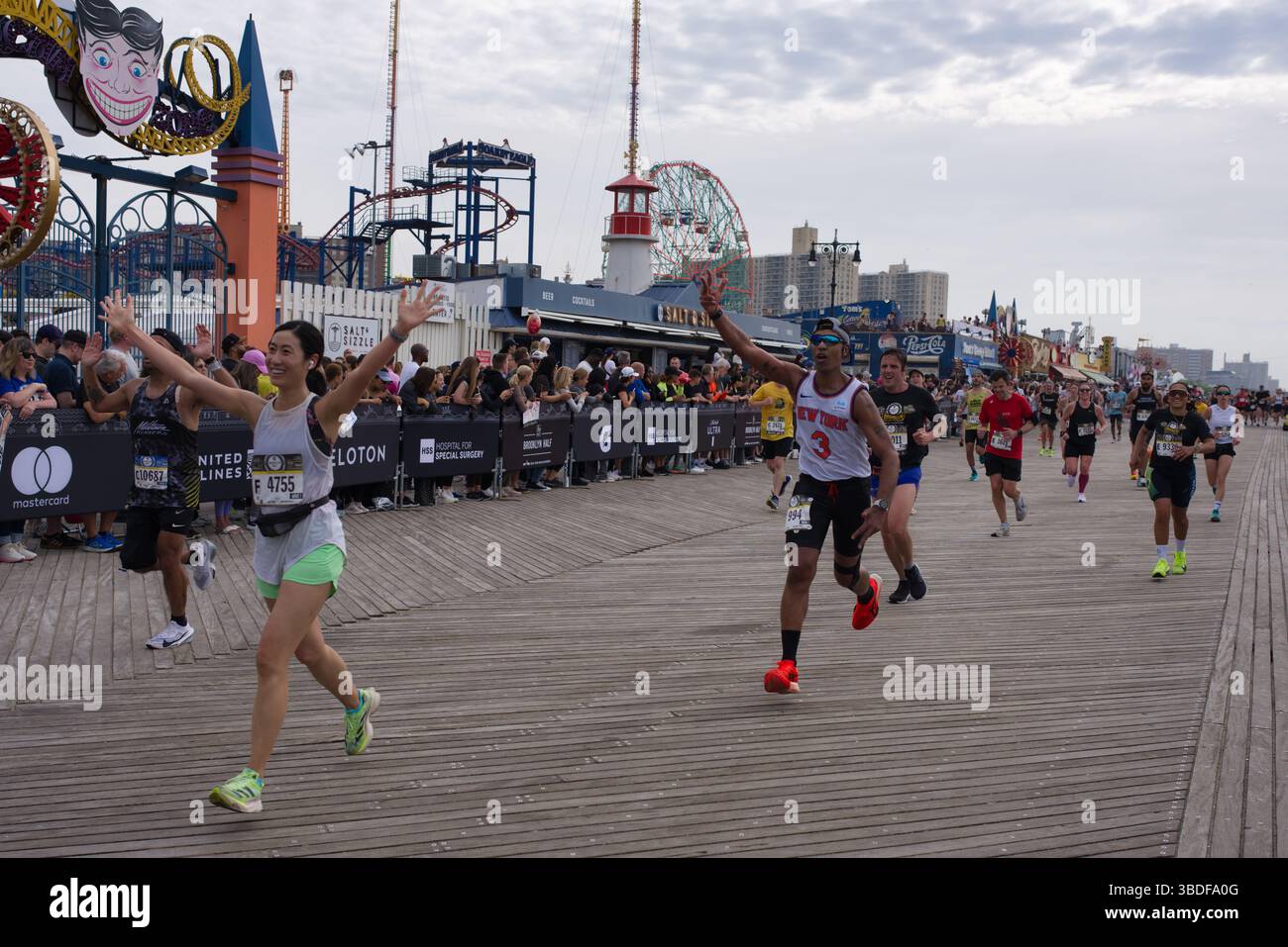 Si svolge una gara di mezza maratona sul lungomare, con corridori di diversi background sullo sfondo del parco divertimenti di Coney Island. Gli spettatori li Foto Stock