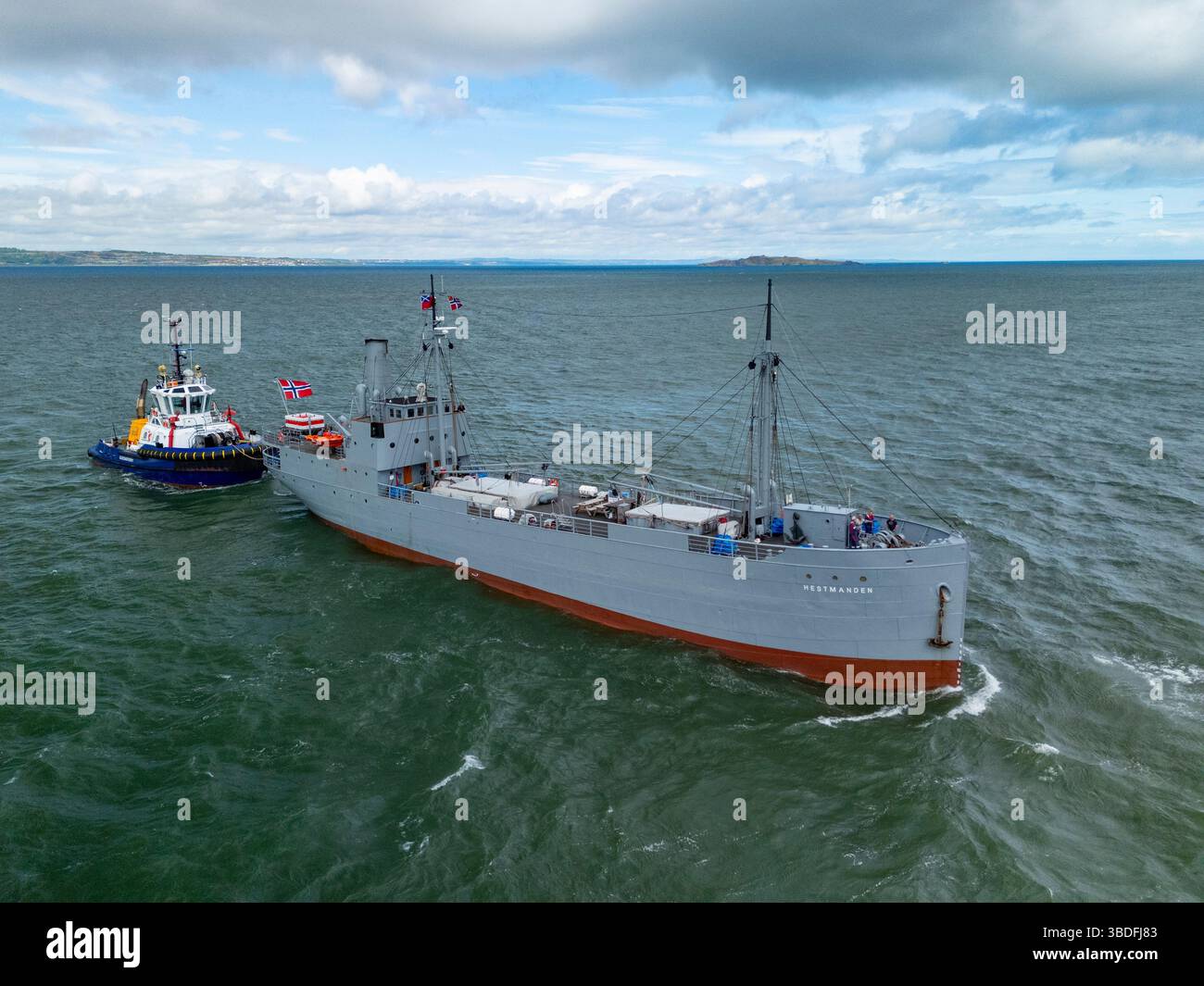 Leith, Edimburgo, Scozia, Regno Unito. 24 maggio 2025. La storica nave norvegese S/S Hestmanden arriva oggi al porto di Leith. La nave mercantile da carico di 114 anni, l'unica nave da carico conservata ad aver navigato in convogli durante la prima e la seconda guerra mondiale, sarà ormeggiata a Leith e aperta al pubblico. Soprannominata “la nave fortunata” per i convogli sopravvissuti in tempo di guerra in due conflitti globali, la Hestmanden è l’unica nave rimasta degli oltre 1.000 che hanno costituito la flotta di Nortraship durante la seconda guerra mondiale. Iain Masterton/Alamy Live News Foto Stock