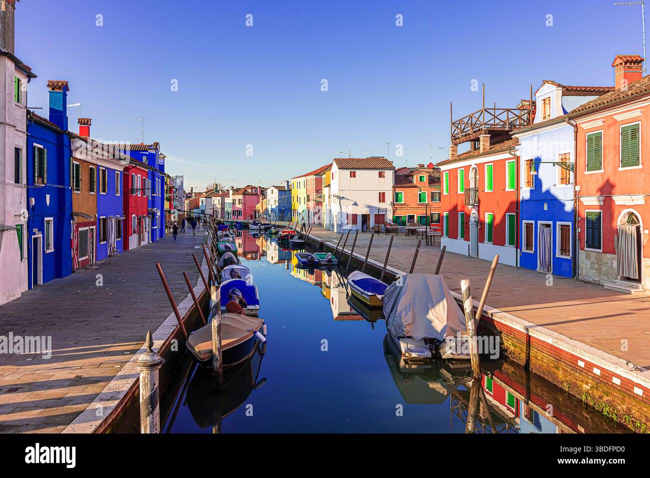 Gli affascinanti canali di Burano con le barche ormeggiate al molo Foto Stock