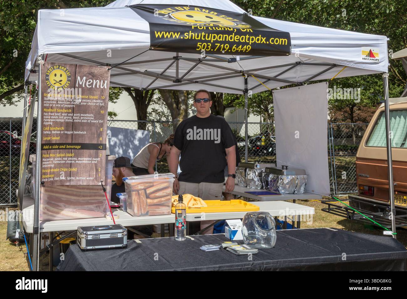 The Big Float, Portland, Oregon - 14 luglio 2018. Un uomo si trova di fronte alla tenda "Shut Up and Eat", pronto a servire panini e contorni. Foto Stock