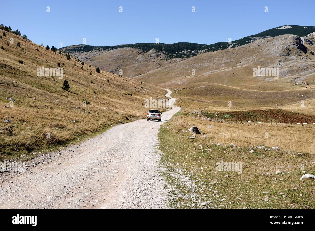 Un'auto guidata su una lunga e tortuosa strada in una valle tra le montagne in autunno, Lukomir, il monte Bjelasnica, Bosnia ed Erzegovina Foto Stock