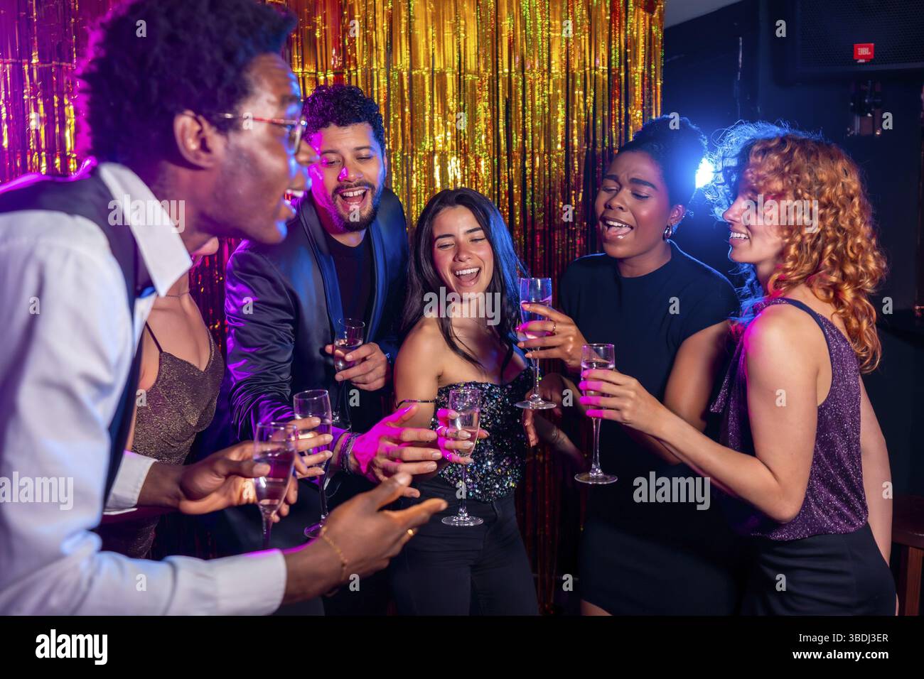 Gruppo di allegri amici multietnici brindando con flute di champagne, godendosi la vita notturna e festeggiando insieme al nightclub Foto Stock