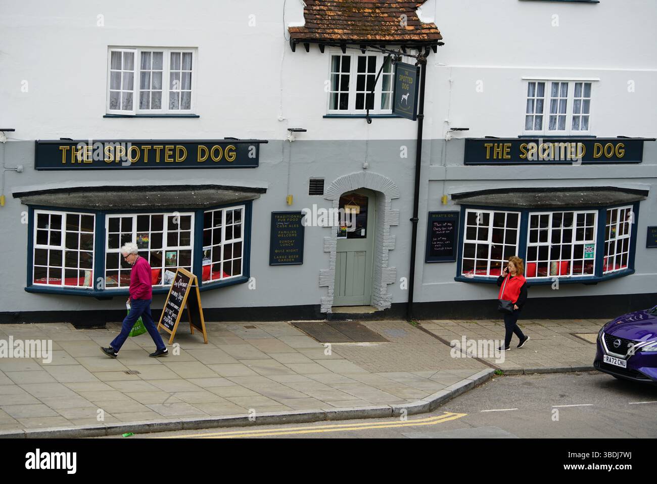 Classico pub inglese esterno con passanti osservati in una strada tranquilla. Dorking, Regno Unito Foto Stock