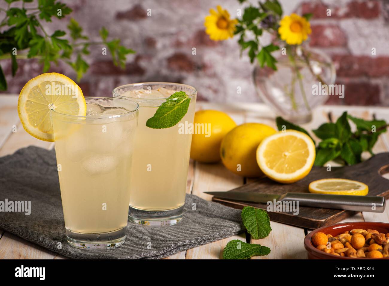 Bicchieri di ghiaccio con bibita al limone a base di succo di frutta, accanto a un tagliere con fette di limone. Primo piano. Foto Stock