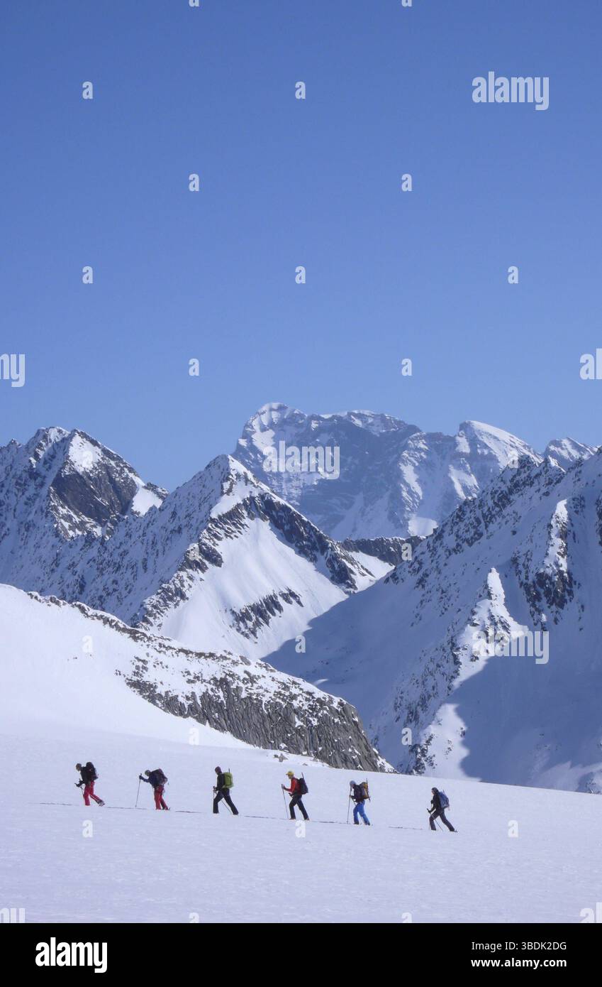 Gruppo di sciatori di fondo in viaggio verso un'alta vetta alpina in una splendida giornata invernale nelle Alpi svizzere vicino a Disentis Foto Stock
