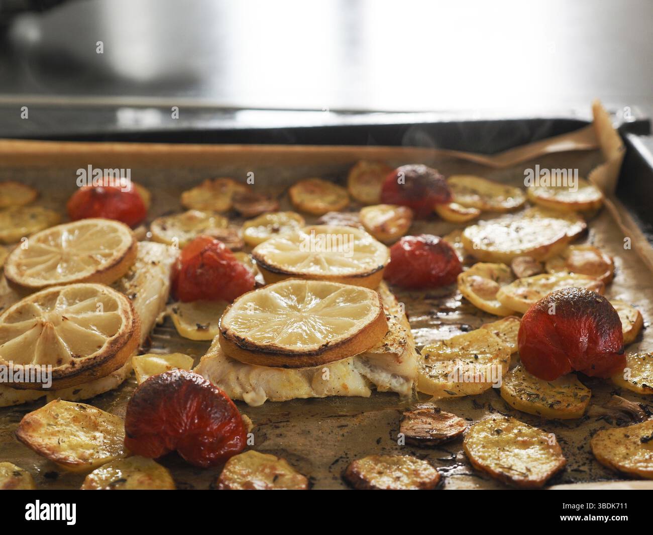 Filetto di merluzzo guarnito con timo, aglio e pomodori, preparazione di un piatto sano. Concetto di cibo sano Foto Stock