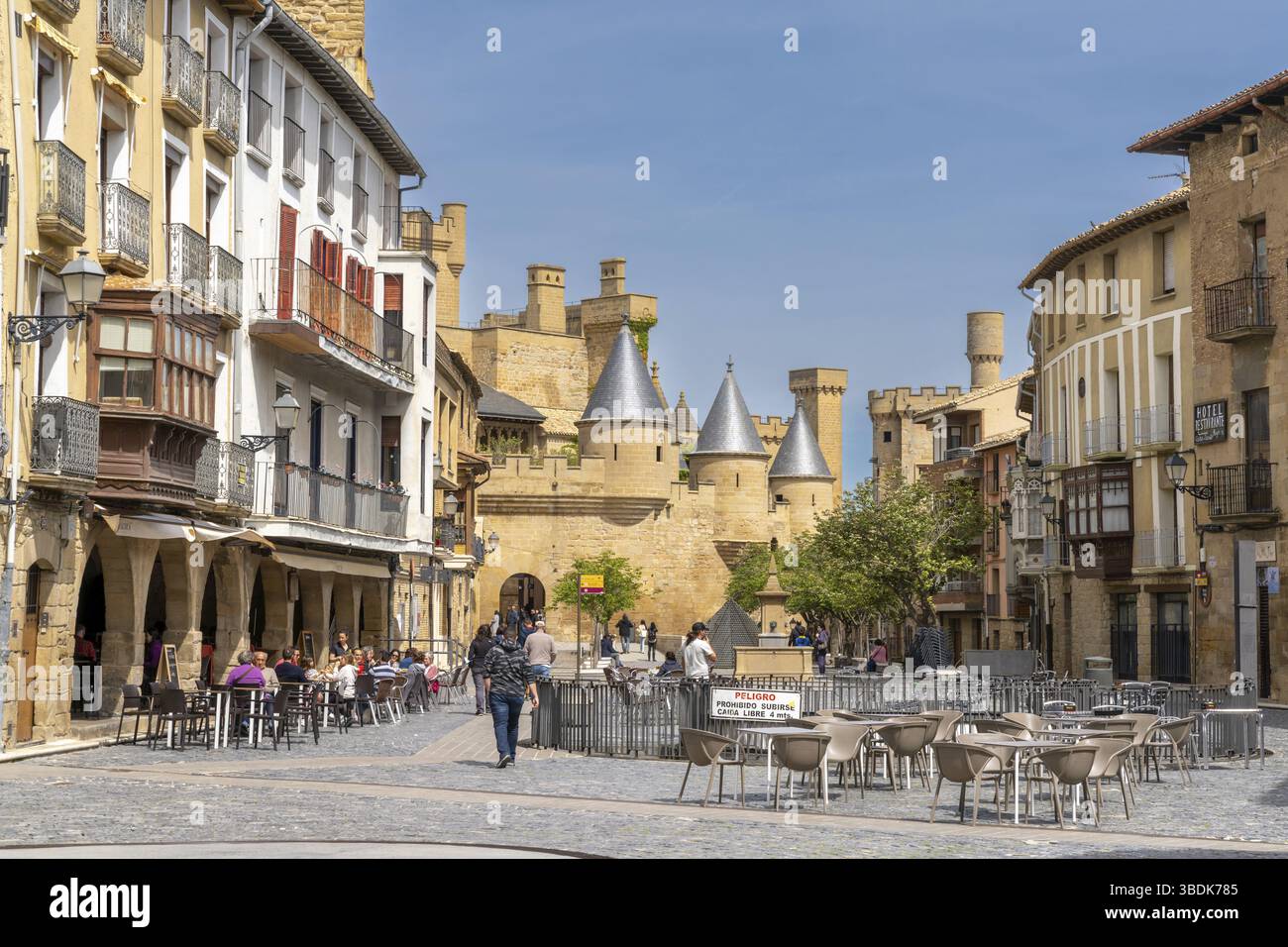 Olite, Spagna - 30 Aprile, 2022: I turisti godono di una visita alla storica Olite in una bella giornata estiva con il castello Palacio Real sullo sfondo Foto Stock