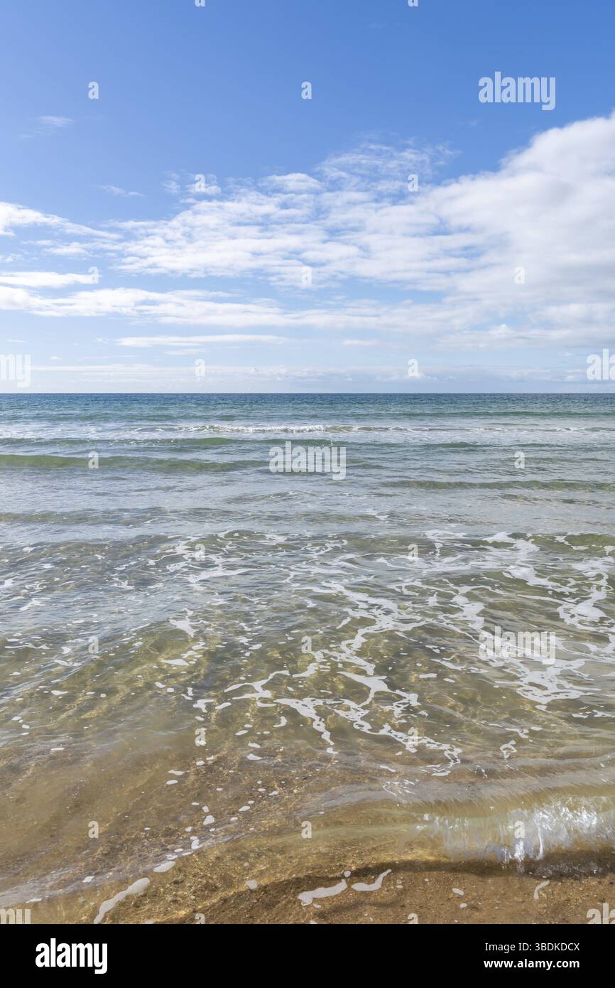 Vista verticale delle acque cristalline dell'oceano tropicale con le onde una spiaggia di sabbia dorata Foto Stock