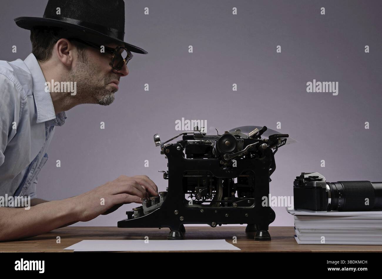 Agente con uno scrittore (vecchio tipo) e una macchina fotografica vintage in un ufficio buio Foto Stock