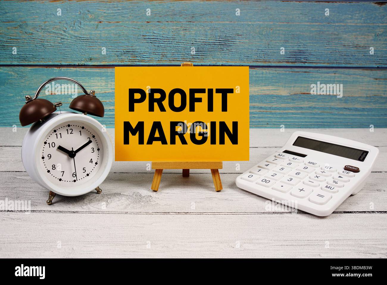 Testo del margine di profitto scritto su carta con calcolatrice e sveglia su sfondo in legno Foto Stock